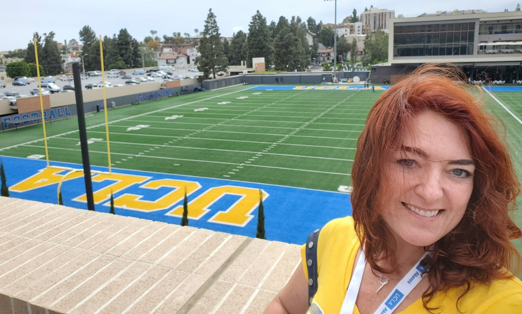 A smiling selfie of Caroline Smith in front of the UCLA football practice field.